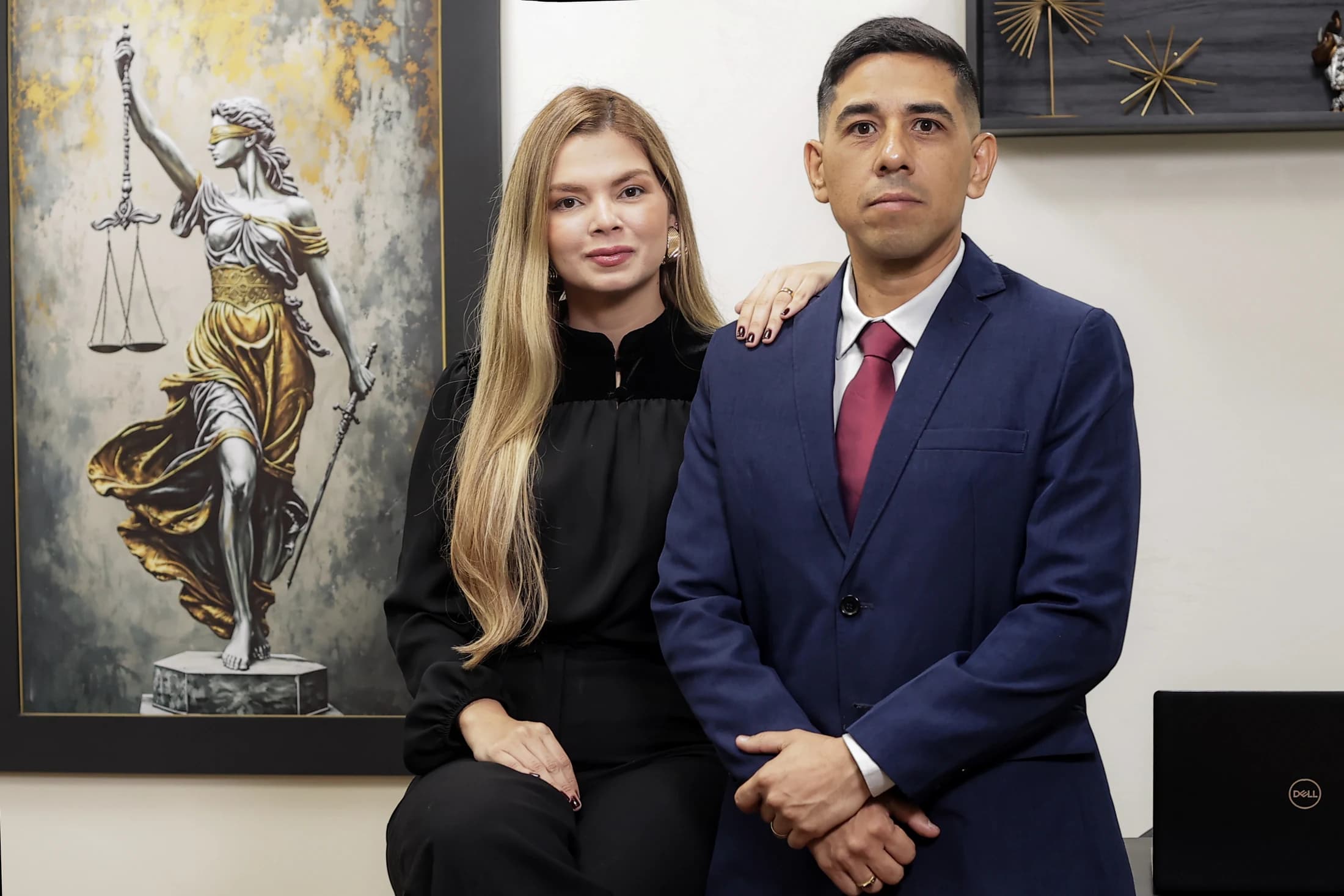 Dois integrantes da equipe do MSC Advocacia na sala de atendimento, ao lado de um quadro da Justiça.